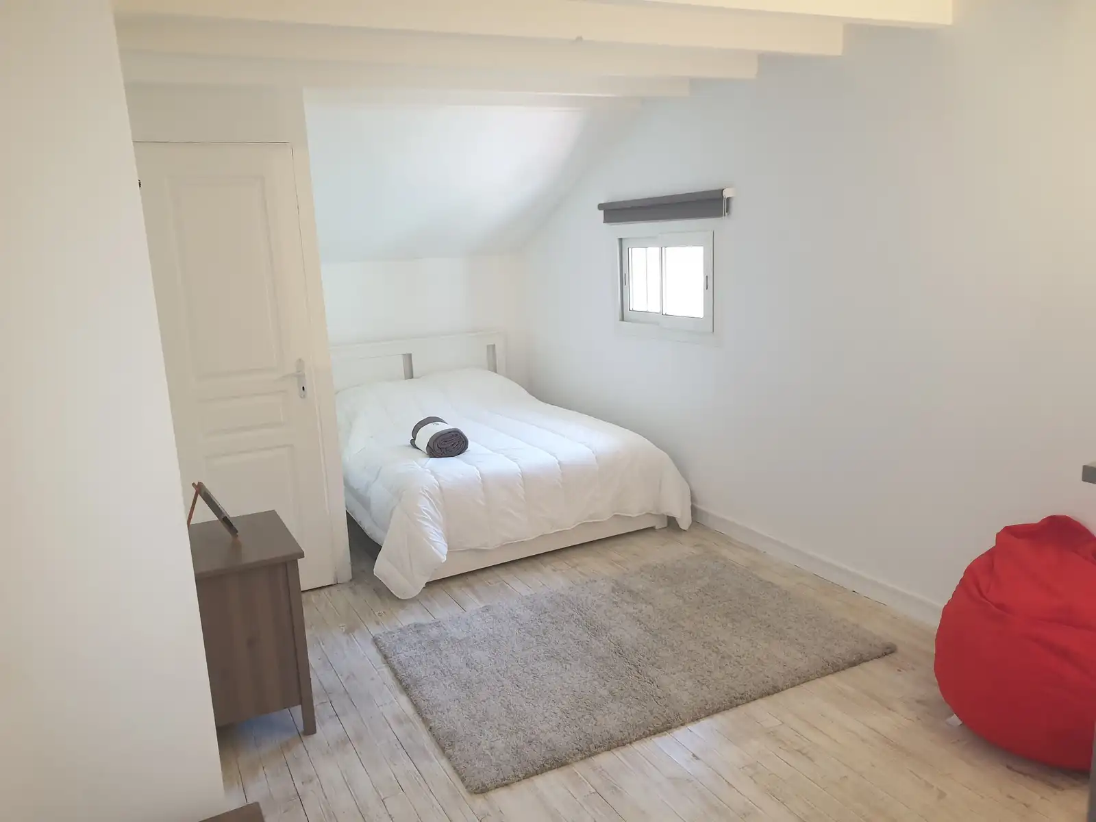 Chambre sous plafond incliné avec lit double et commode