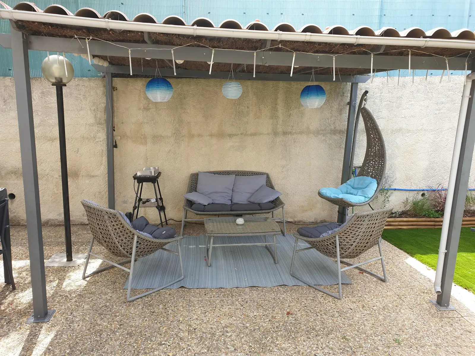 Coin détente sous pergola avec fauteuils et barbecue