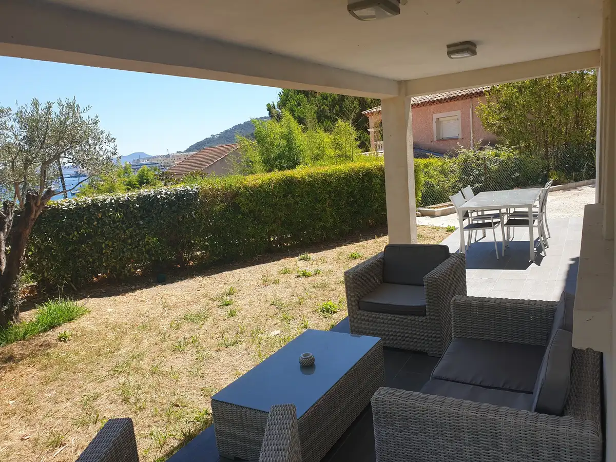 Terrasse couverte avec salon de jardin face à la haie et à la mer