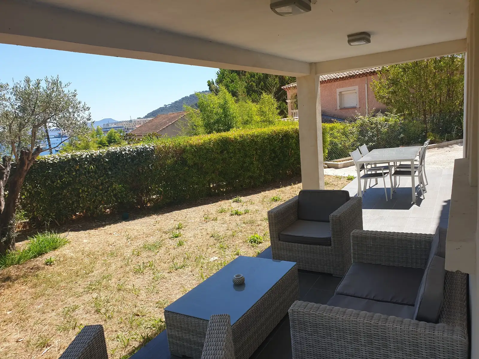 Terrasse couverte avec salon de jardin face à la haie et à la mer